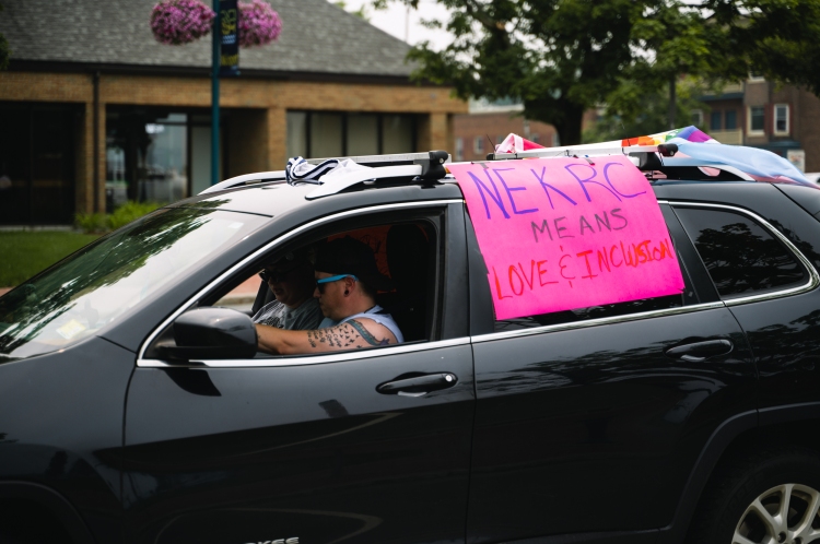 Black SUV with flag and sign: NEKRC means love and inclusion