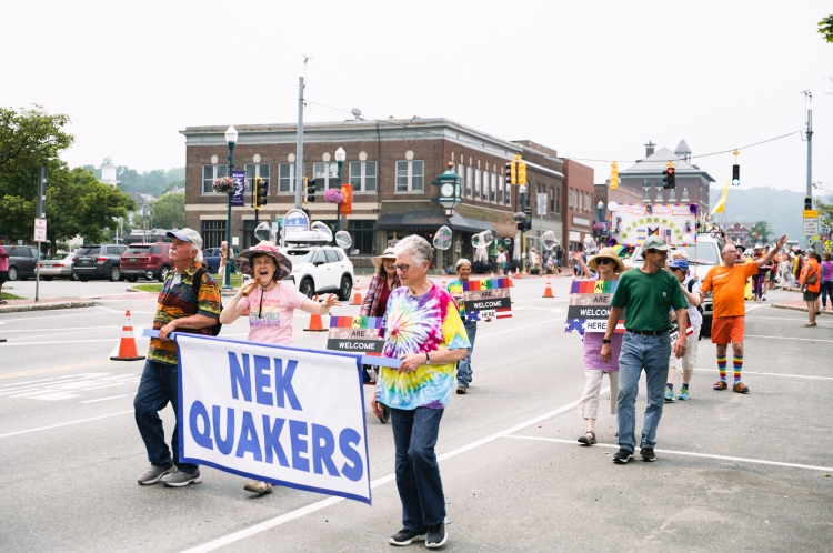 People in tie-dye shirts carrying NEK Quakers banner