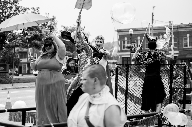 People smiling and blowing bubbles on float